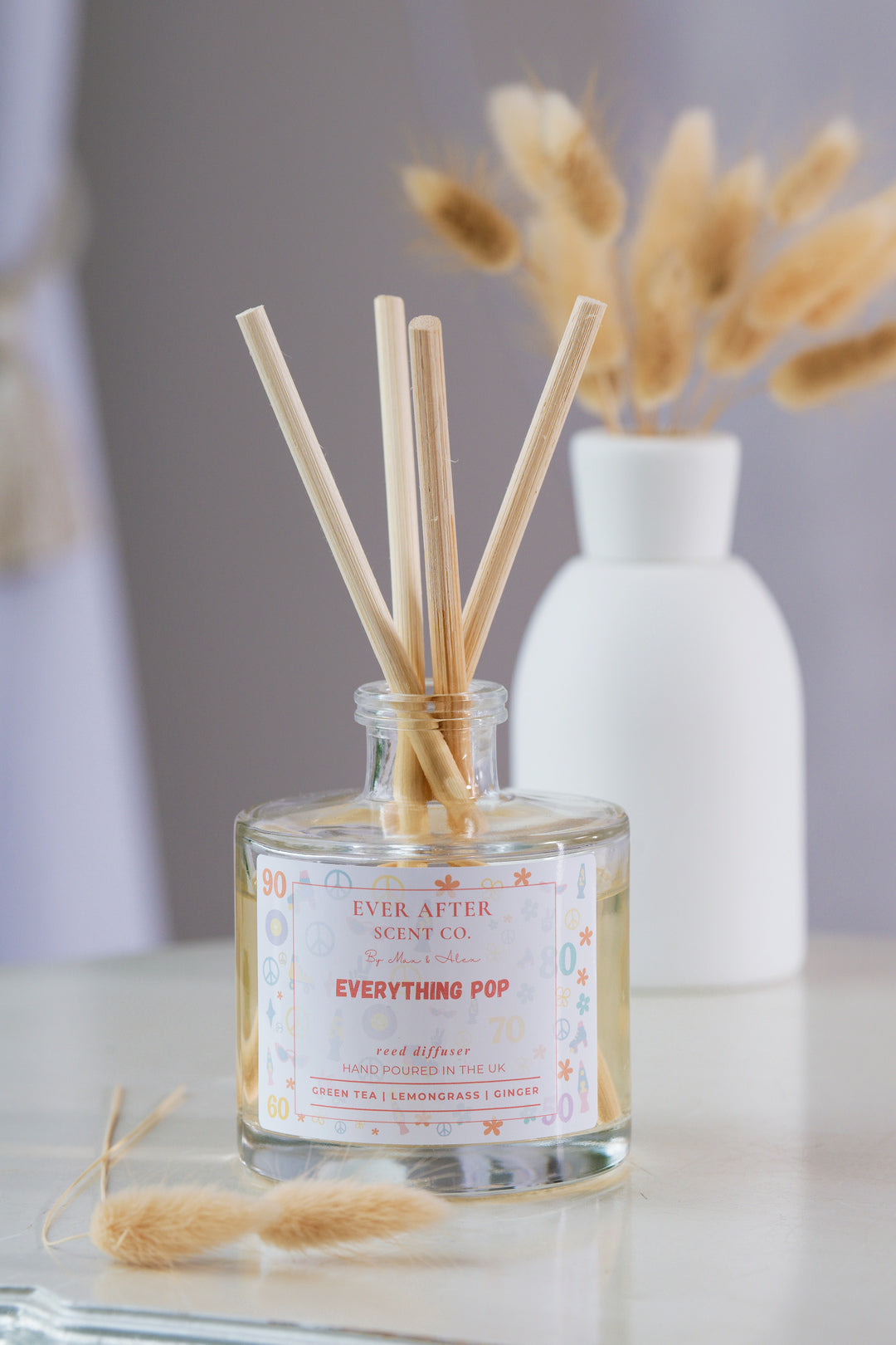 Ever After Scent Co Everything POP Reed diffuser with sticks in a glass bottle on a marble surface with a blurred background