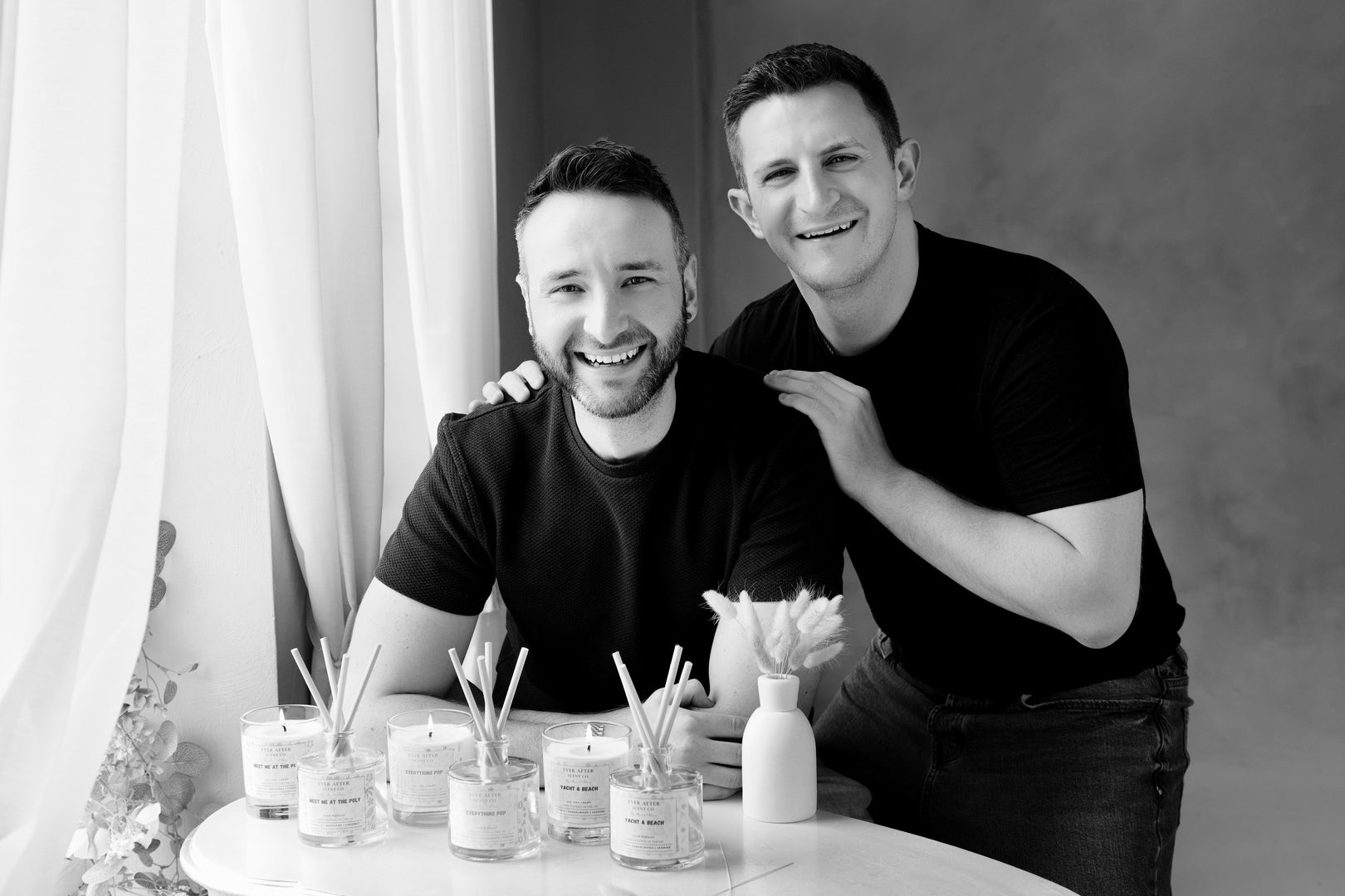 Max & Alex from Ever After Scent Co, posing in at a table with the collection of candles and reed diffusers inspired by Disney resort scents.