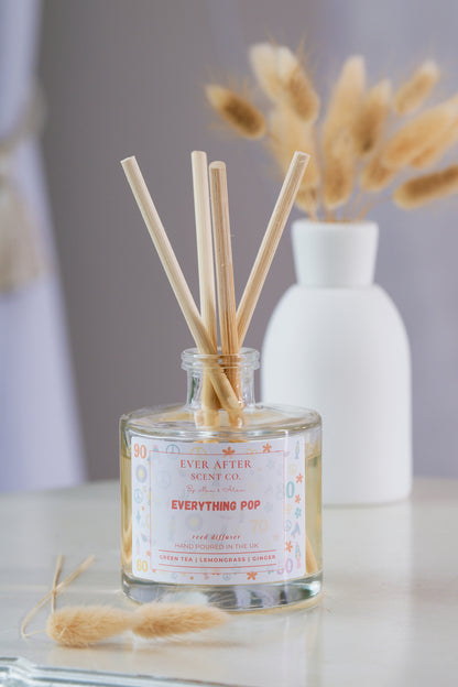 Ever After Scent Co Everything POP Reed diffuser with sticks in a glass bottle on a marble surface with a blurred background